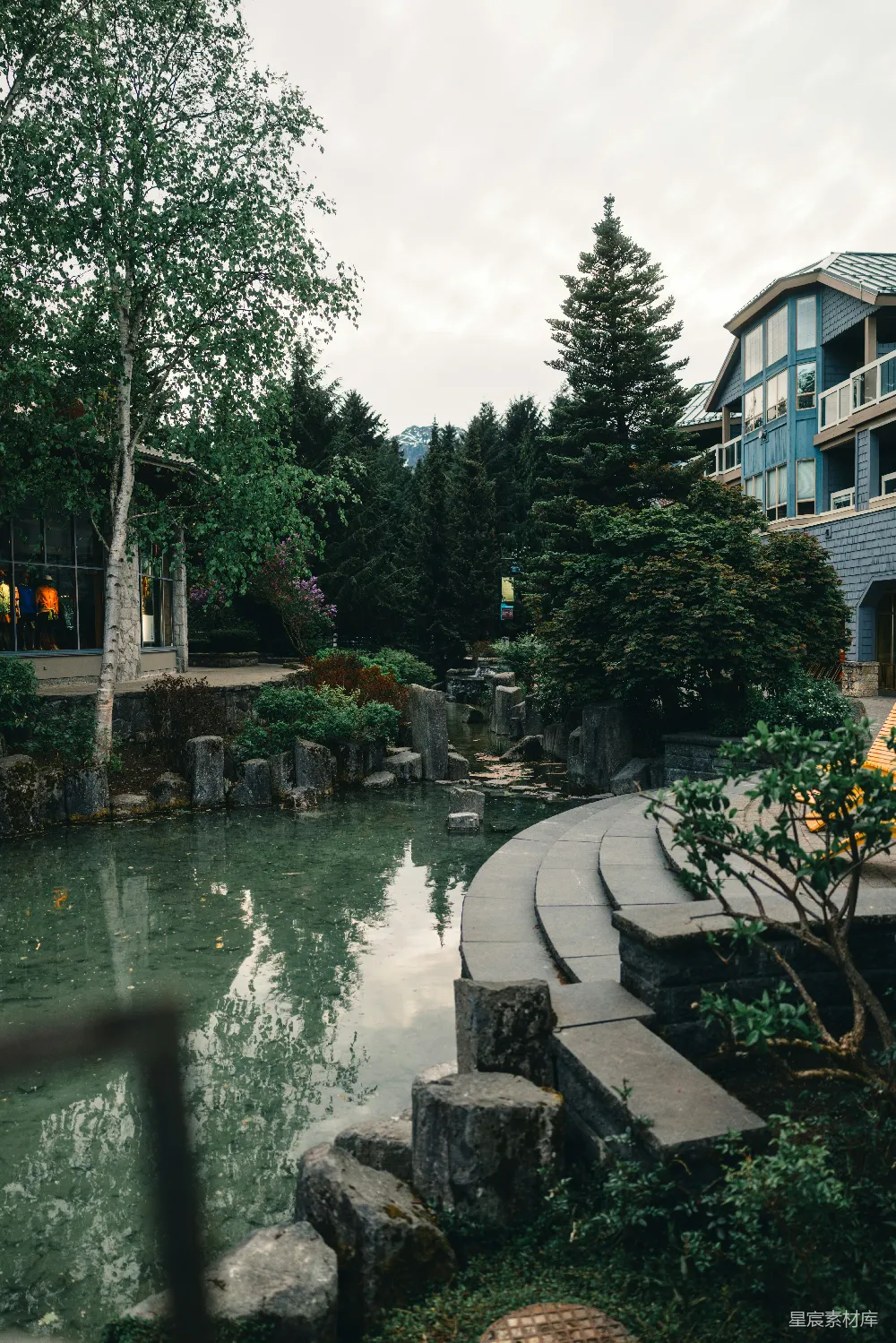 高清摄影  宁静的池塘被树木和建筑物环绕。