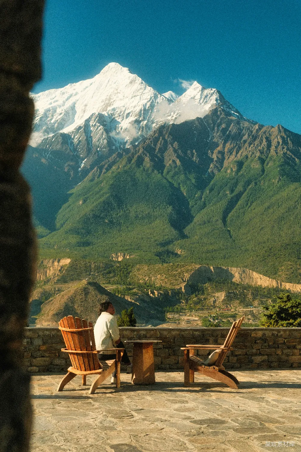 高清摄影  这个人坐在露台椅上欣赏着山景。