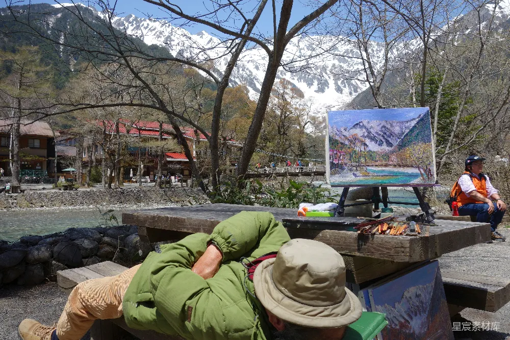 高清摄影  男人在画架旁睡觉，画架上有山景画。