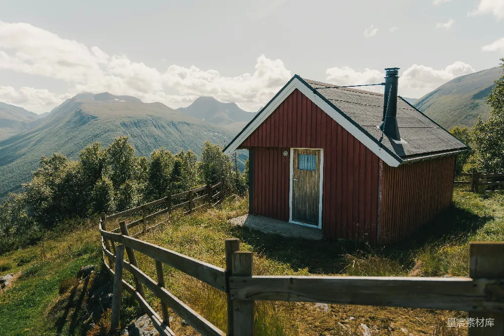 高清摄影  山上有一座红色的小屋，周围有山脉和栅栏。