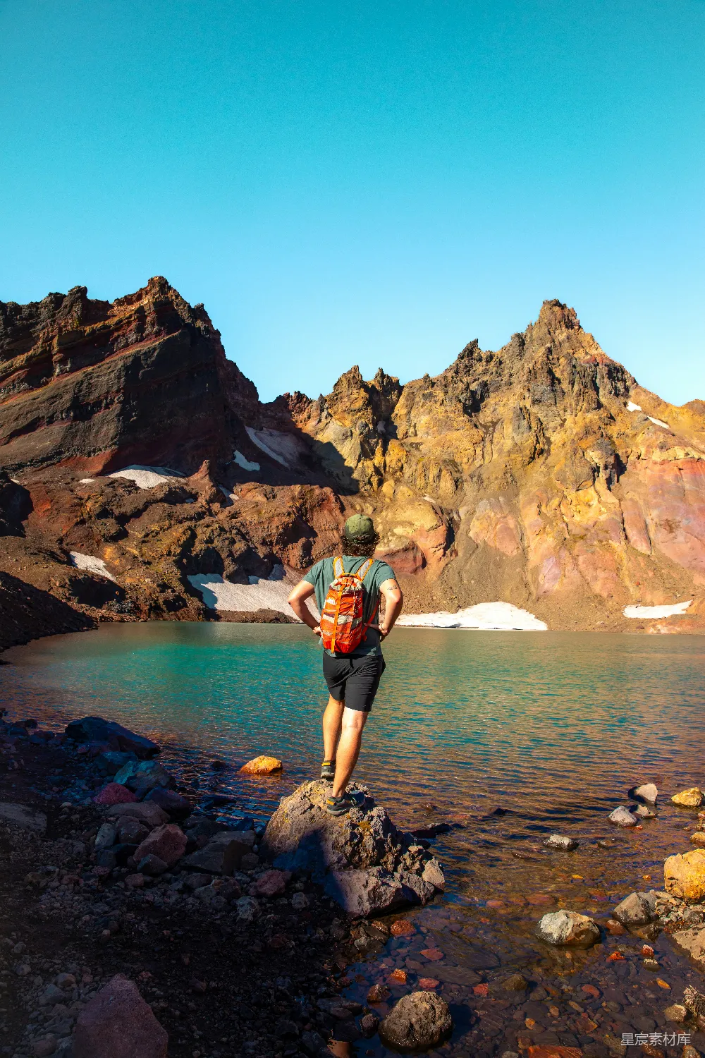 高清摄影 旅行 一个男人站在山顶上，旁边有一片湖。