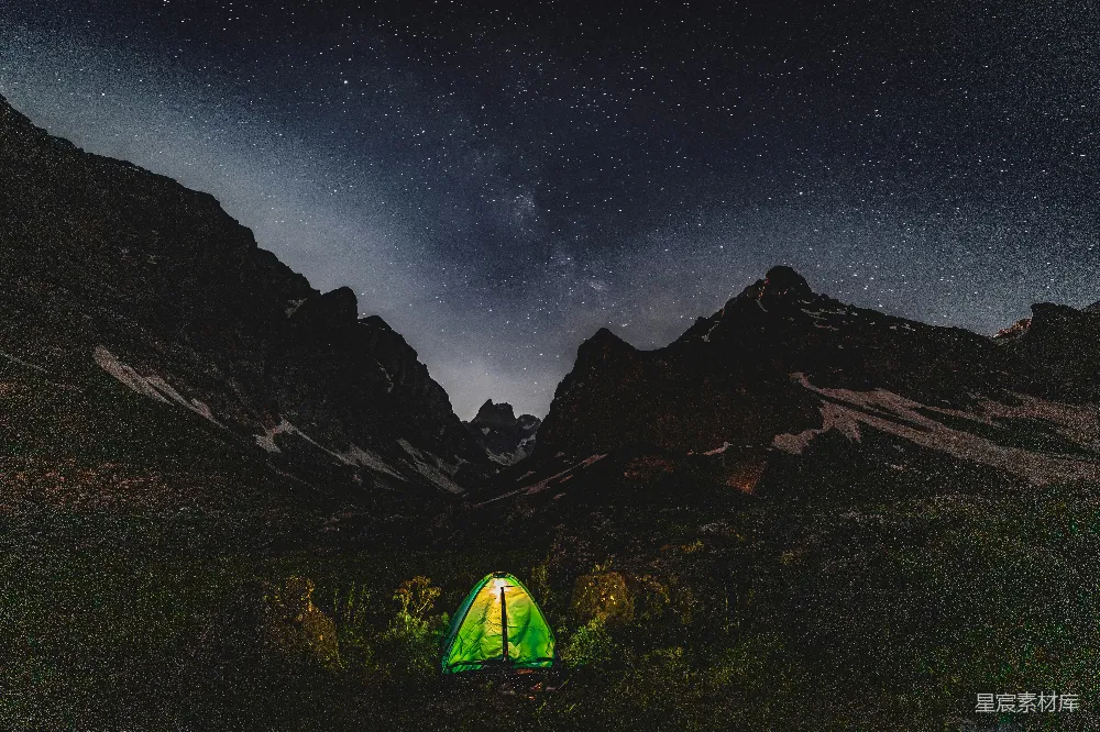 高清摄影  在星空下的黑暗山谷里，帐篷被灯光照亮。