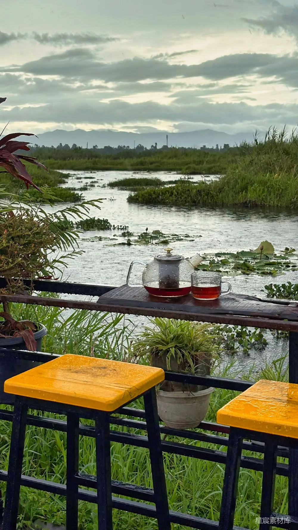 高清摄影  一套茶具放在一张桌子旁，桌子旁边是宁静的河流风景。