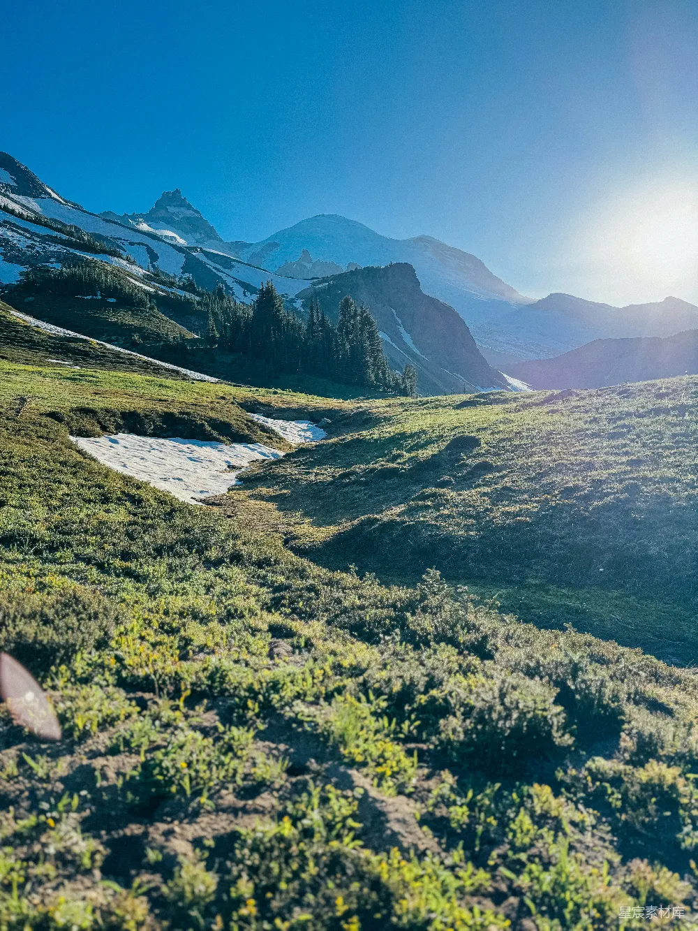 高清摄影  阳光照亮了覆盖着雪斑的草地山景。
