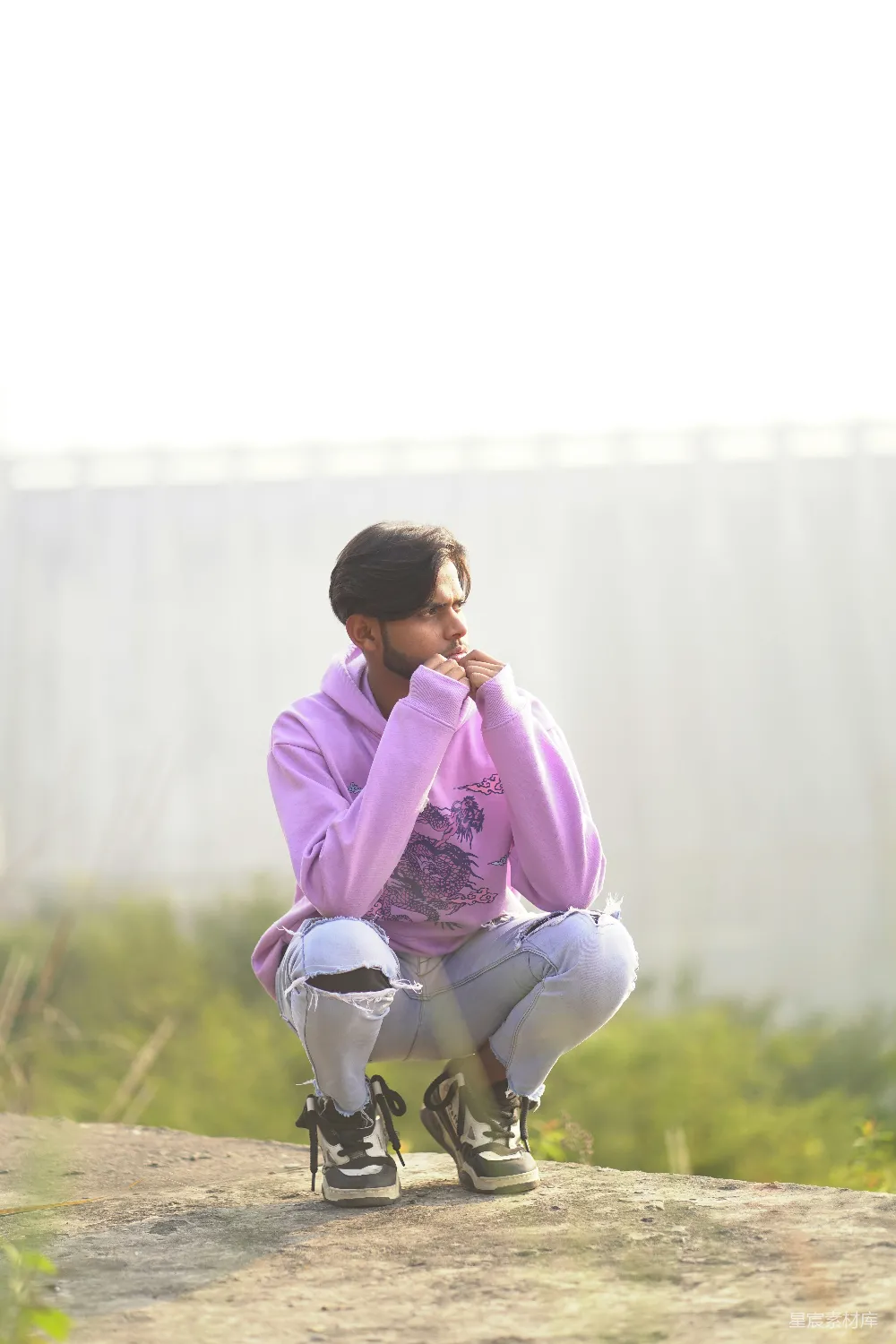 高清摄影  一个男人坐在滑板上，坐在土路上。