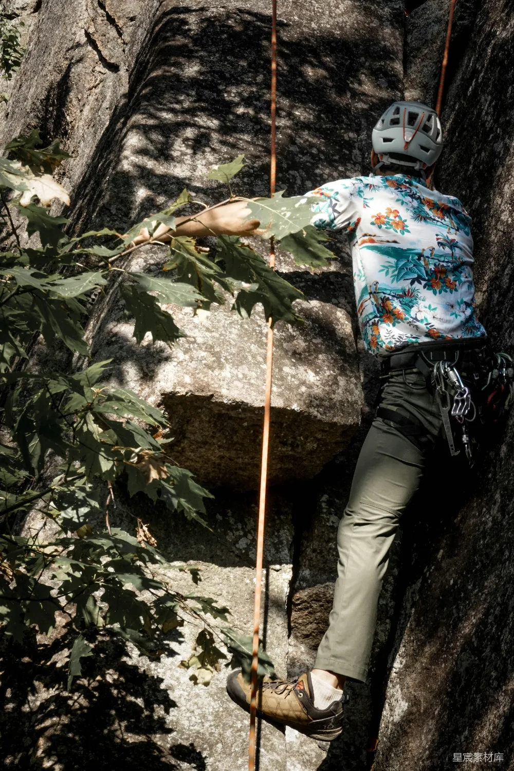 高清摄影  一个男人正攀爬着山的一侧。