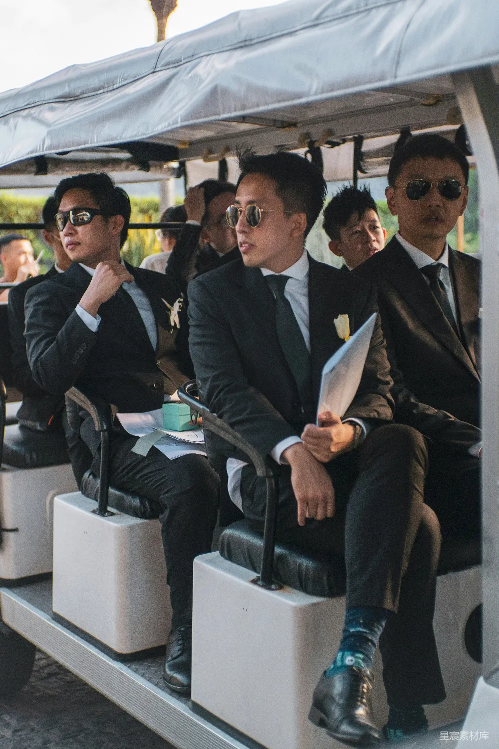 高清摄影  一群穿着西装的男士坐在一辆高尔夫车上