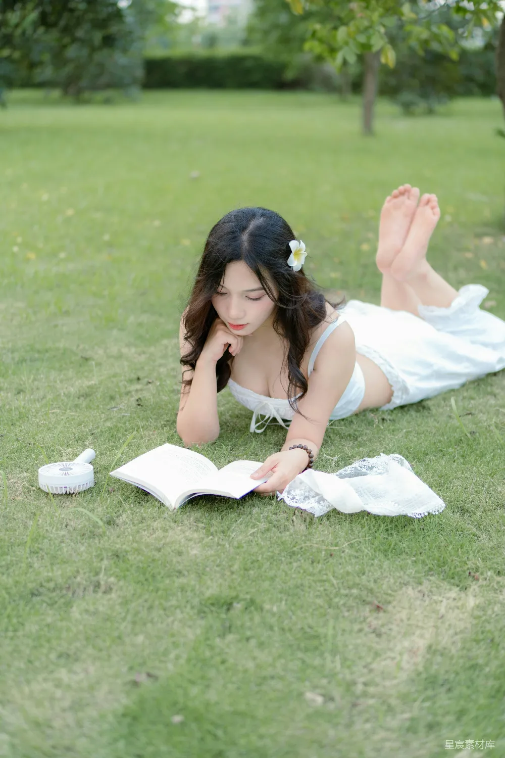 高清摄影  一位女子躺在草地上看书。