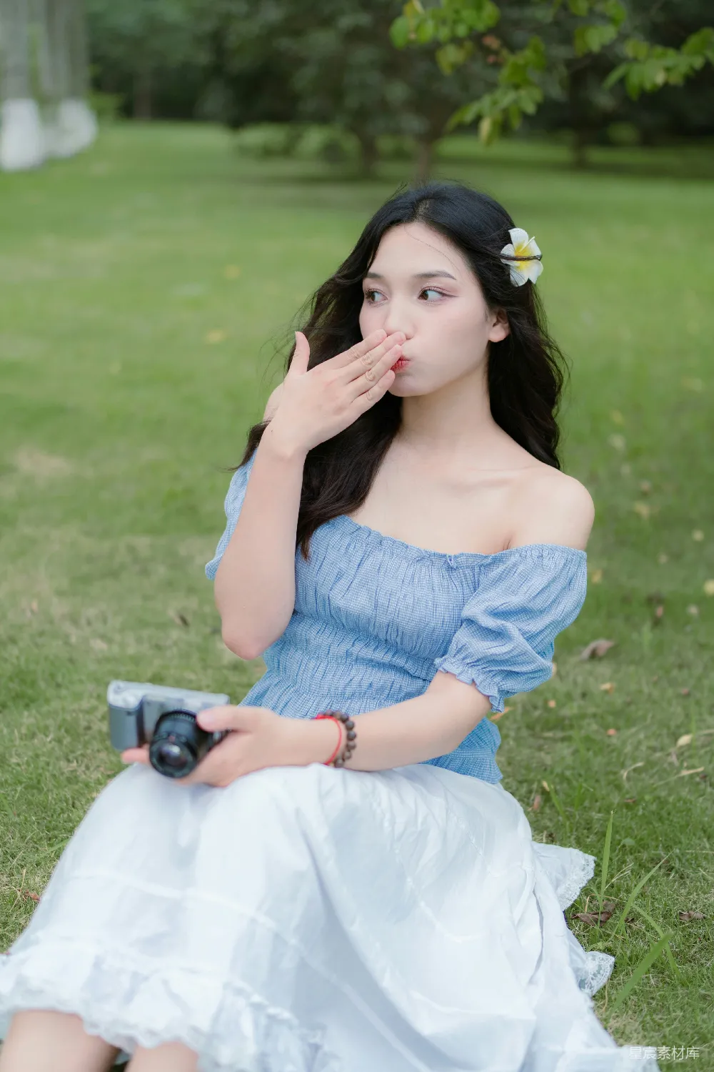 高清摄影  一个女人坐在草地上，拿着相机。