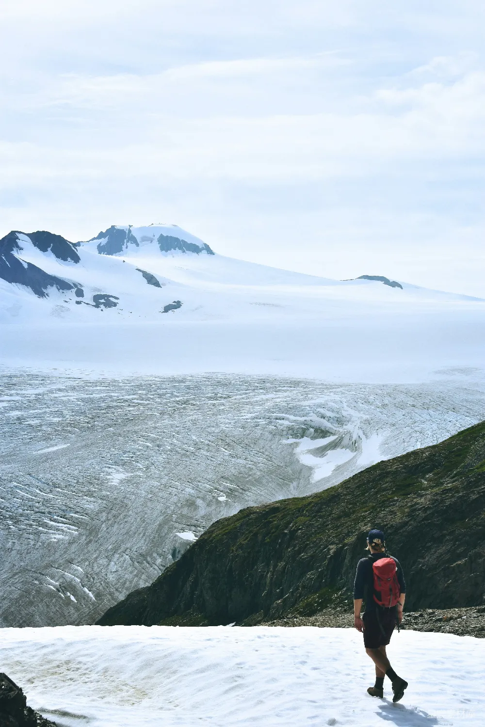高清摄影  男人在雪地里行走，面向着山峰。