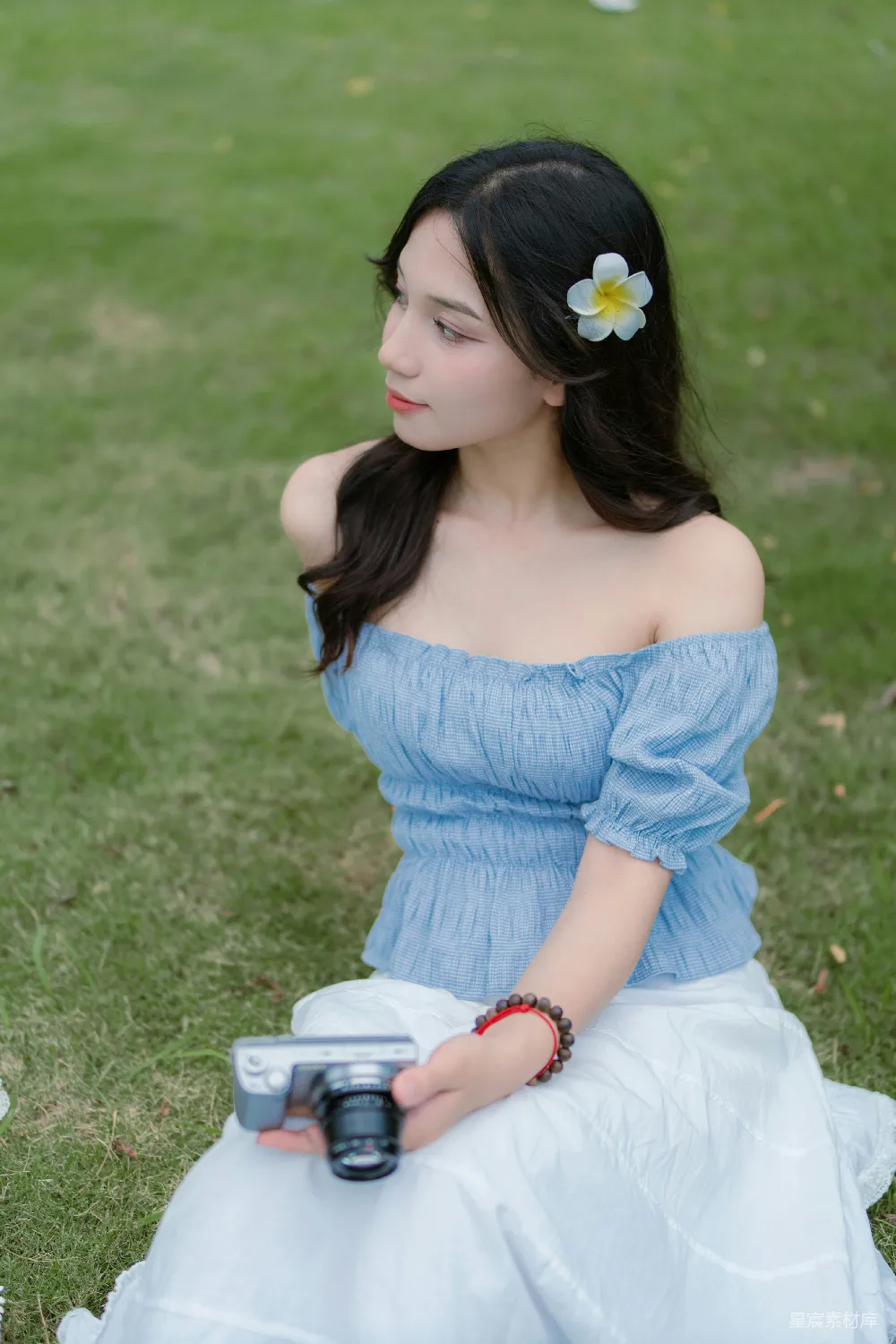 高清摄影  一个女人坐在草地上拿着相机。