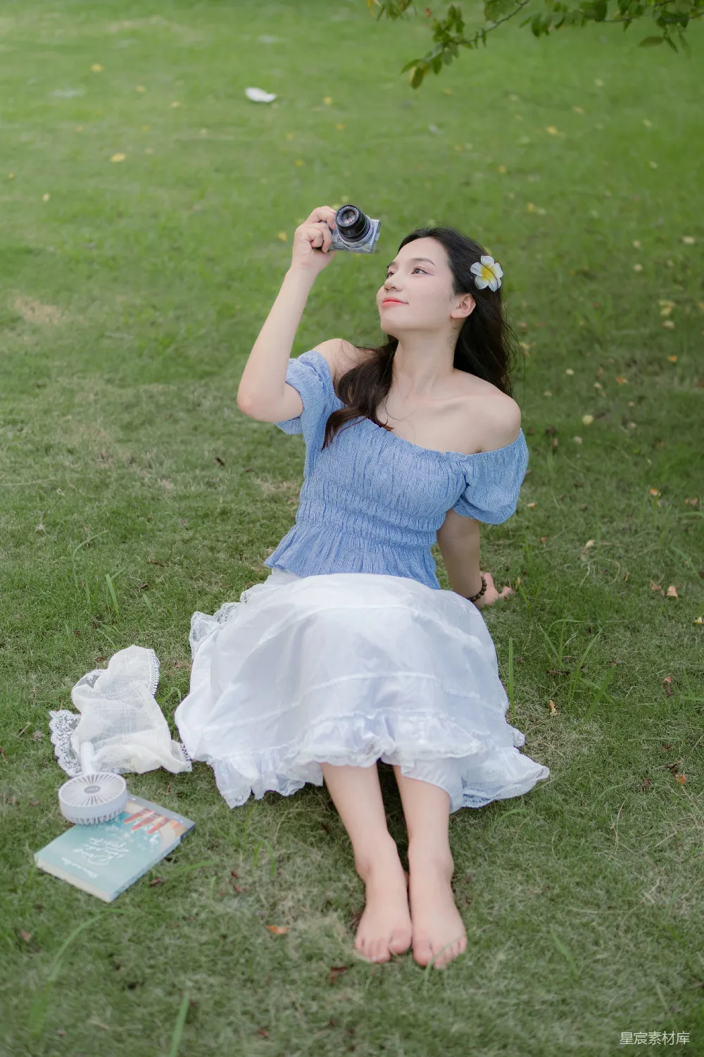 高清摄影  一位穿蓝色连衣裙的女士坐在草地上。