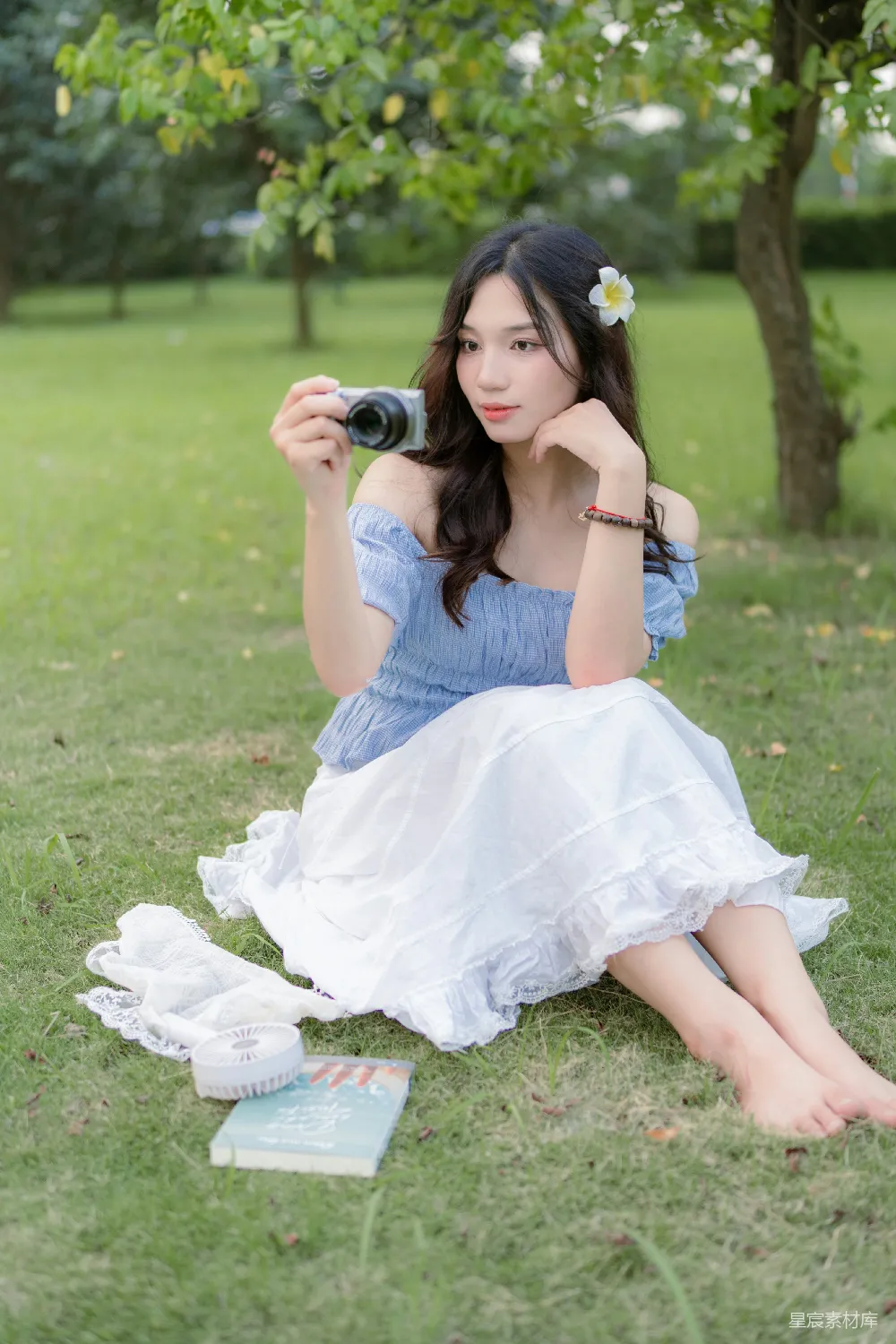 高清摄影  一个女人坐在草地上，手里拿着相机。