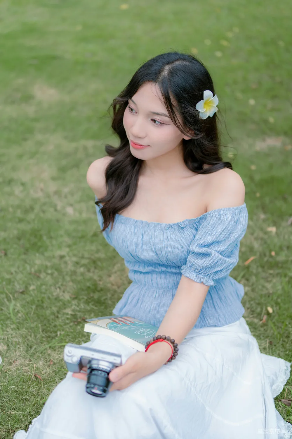 高清摄影  一个穿着蓝色连衣裙的女人坐在草地上。