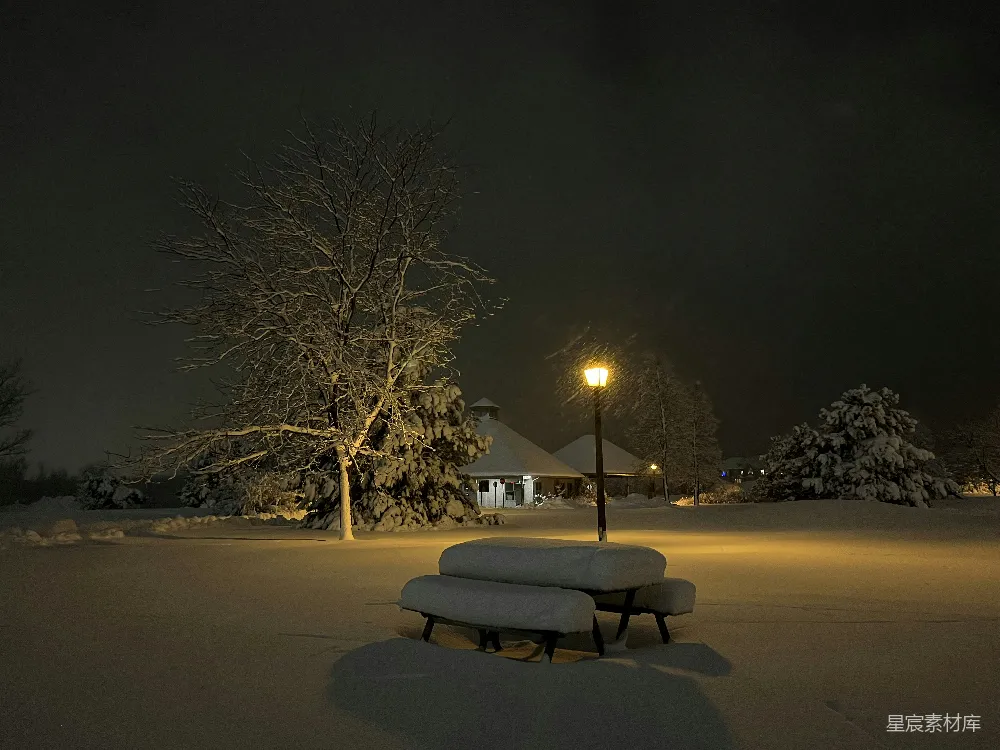 高清摄影  一张公园长椅在夜晚被积雪覆盖。