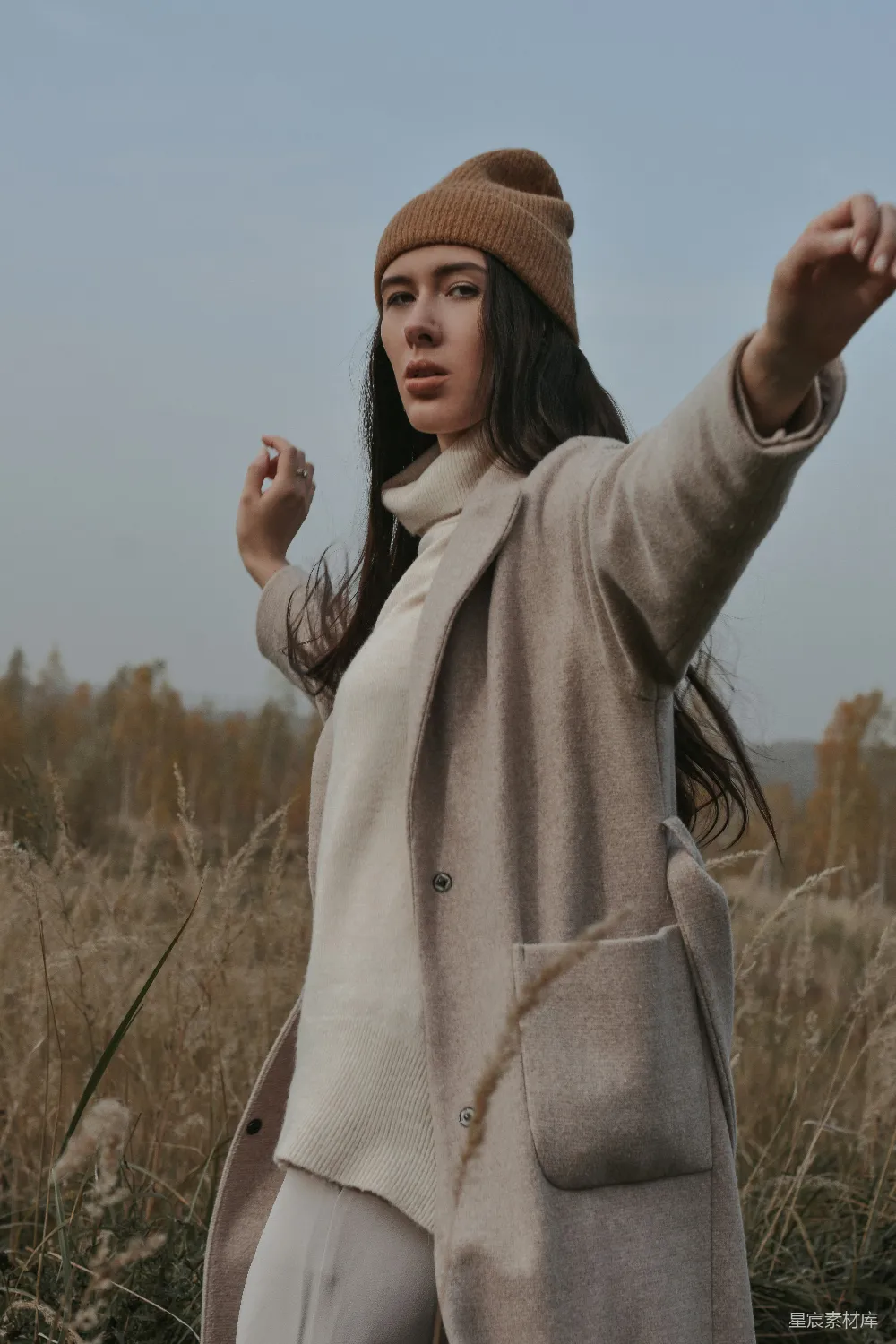 高清摄影  一个女人站在田野里指着什么东西。