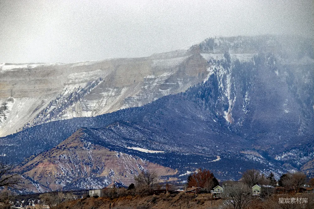 高清摄影  一座被雪覆盖的山，山前有房屋。