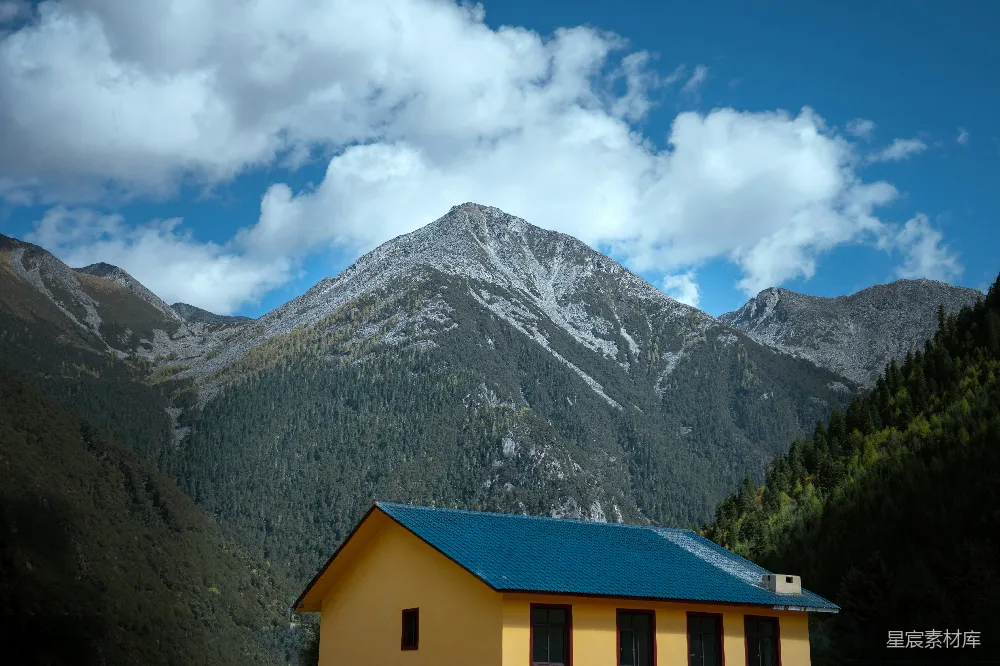高清摄影  一座黄色的建筑，屋顶是蓝色的，山峦在背景中。