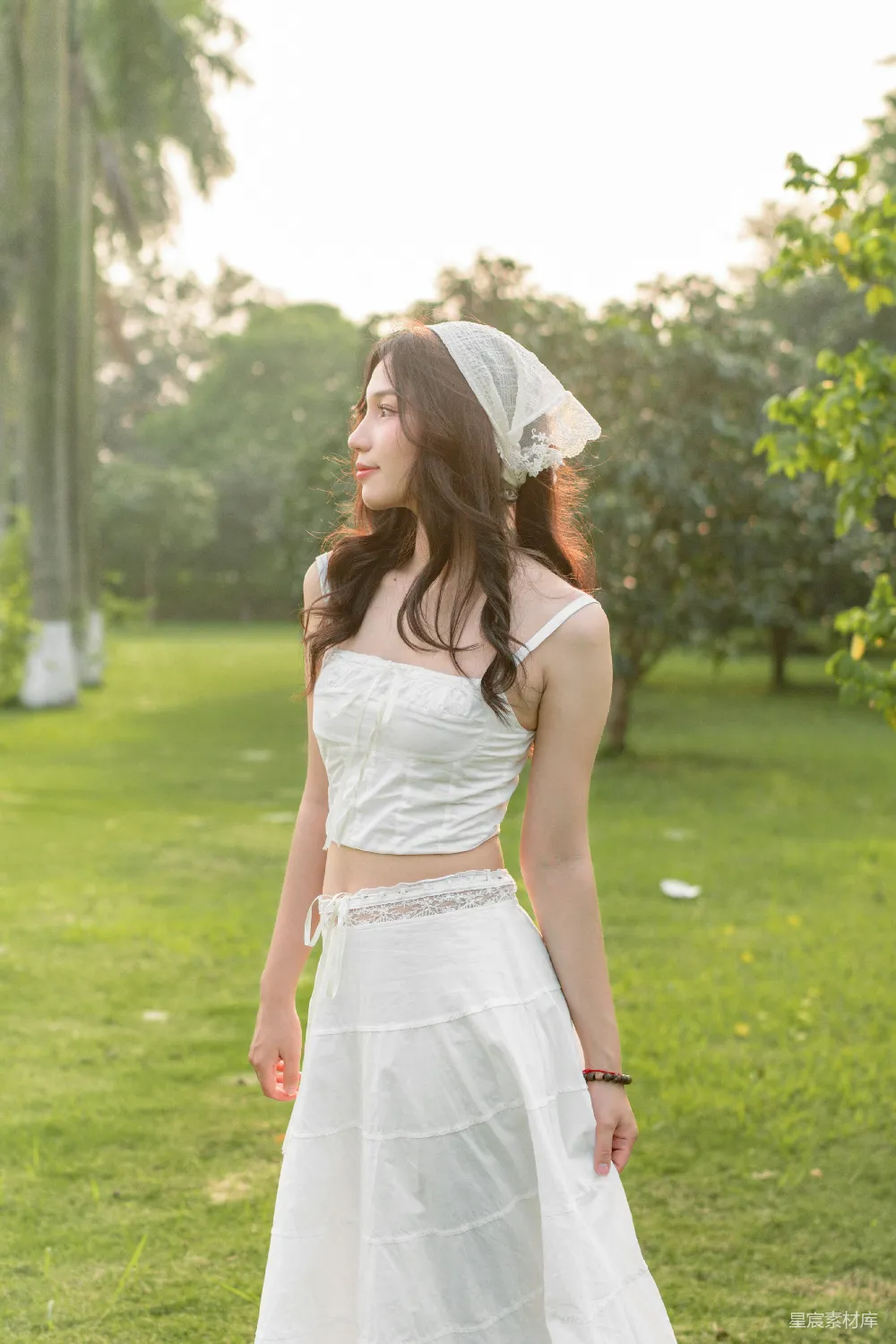 高清摄影  一位穿着白色连衣裙的女士站在草地上。