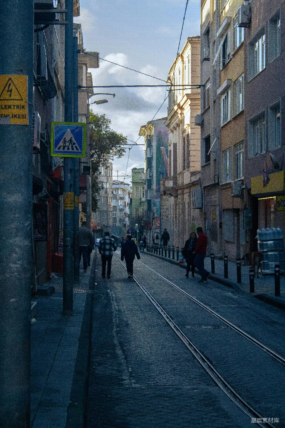 高清摄影  一群人沿着街道行走，街道两旁是高楼大厦。