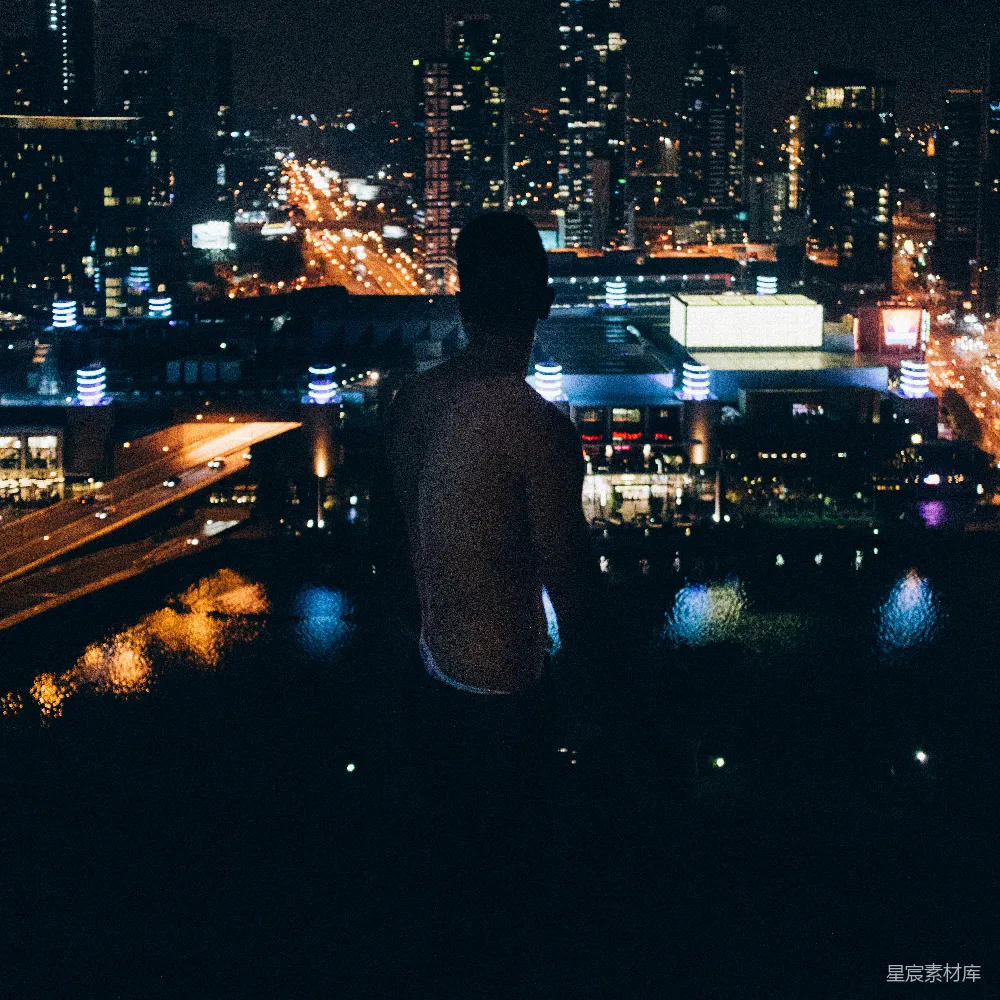 高清摄影  一个男人站在夜晚的城市天际线前。