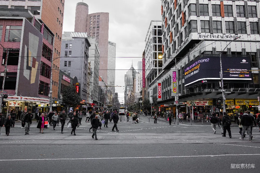 高清摄影  一群人正穿过高楼大厦旁的街道。