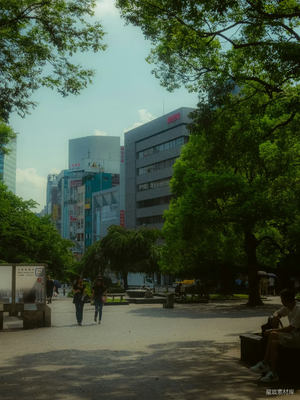 高清摄影  人们在公园里散步，背景是城市建筑。