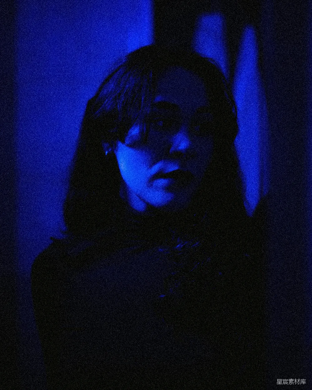 高清摄影  一个女人站在一个黑暗的房间里，有蓝色的光线。