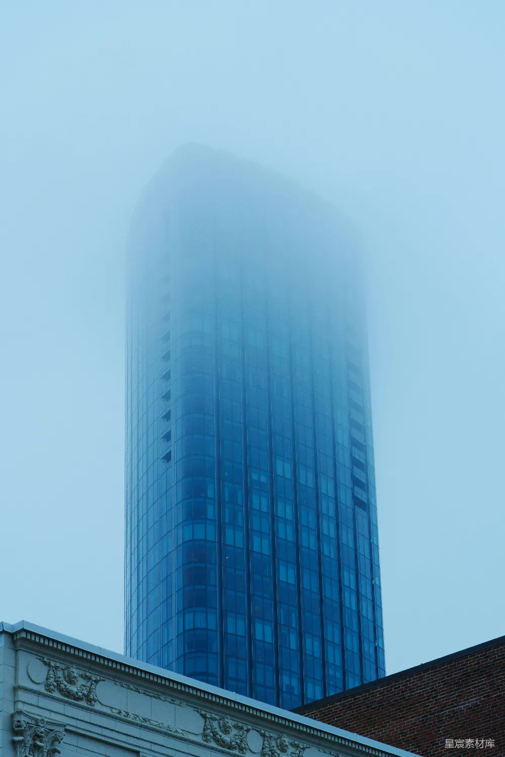 高清摄影  一座非常高大的建筑物，身后是浓雾弥漫的天空。