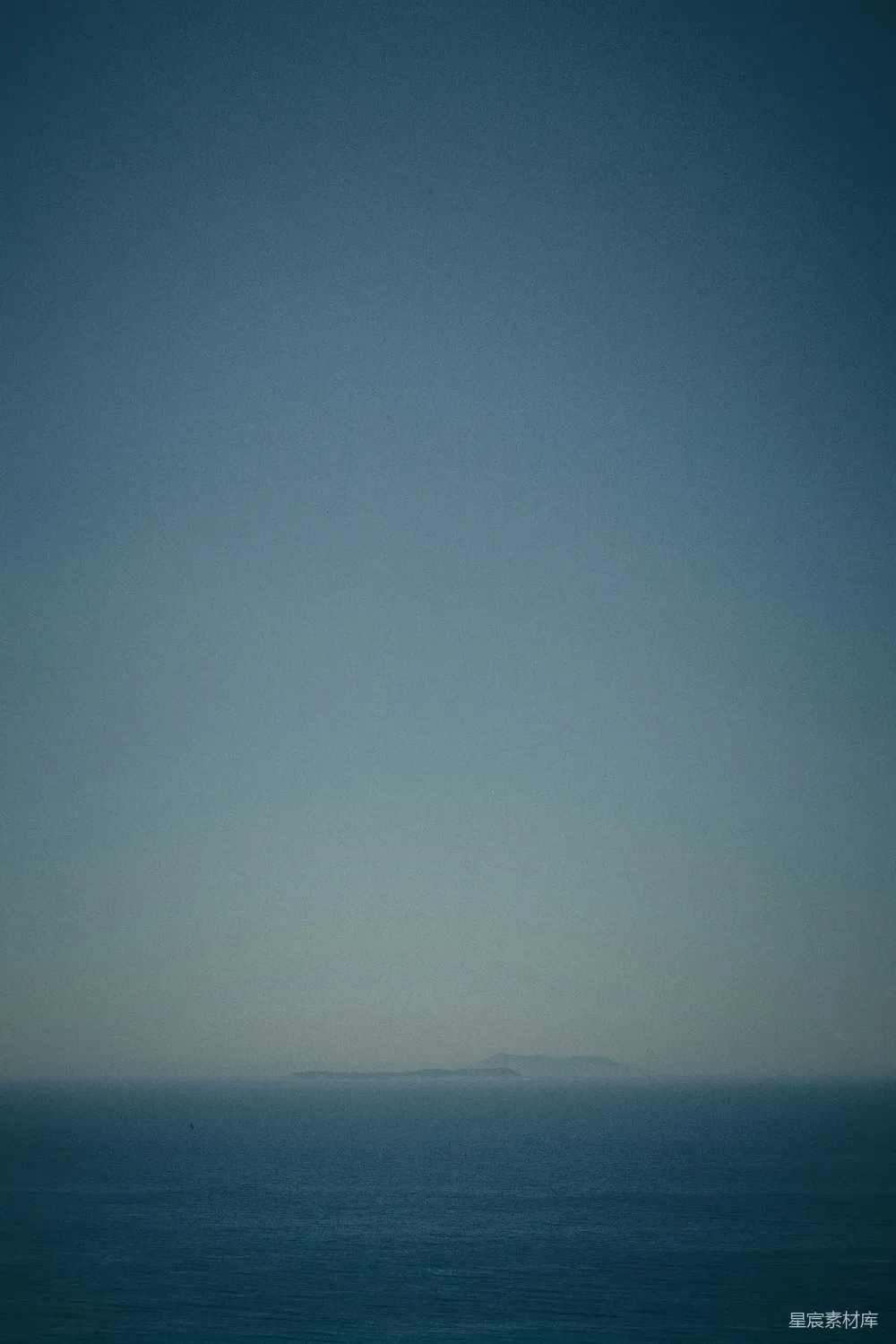 高清摄影  平静的海洋上空是蓝天，远处有一座岛屿。