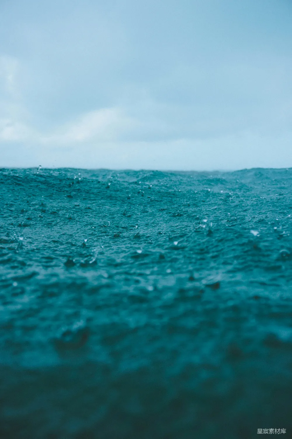 高清摄影  雨滴落在波涛汹涌的蓝色海面上。