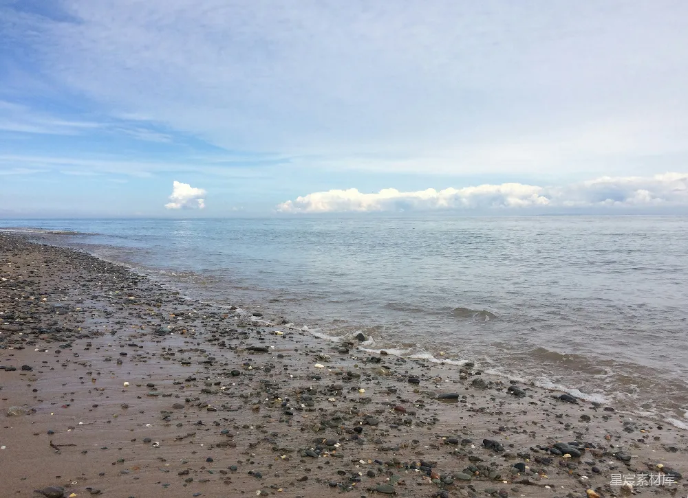 高清摄影  白天蓝天下的海浪拍打着岸边。