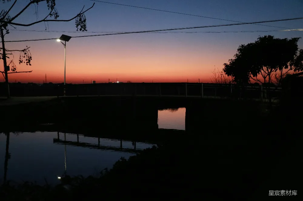 高清摄影  夕阳为黑暗的池塘上方的天空涂上了一抹色彩。