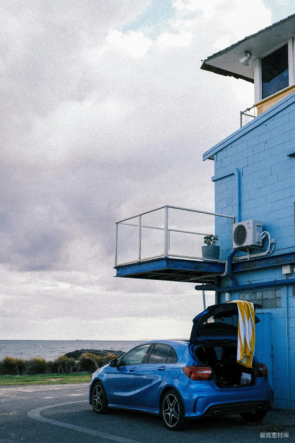 高清摄影  白天，黑色汽车停在白色混凝土建筑旁边。