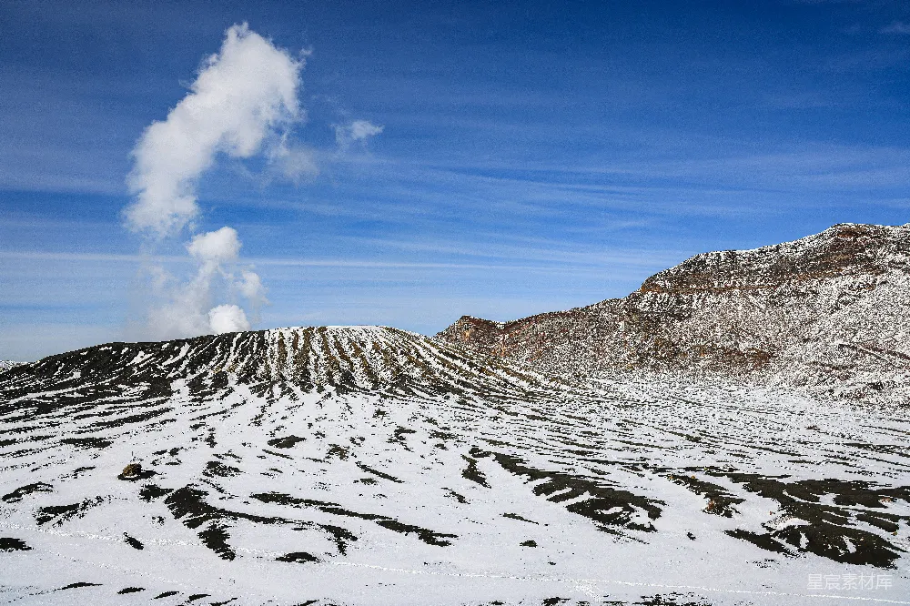 高清摄影  一座被雪覆盖的山峰，从它冒出一缕烟雾。