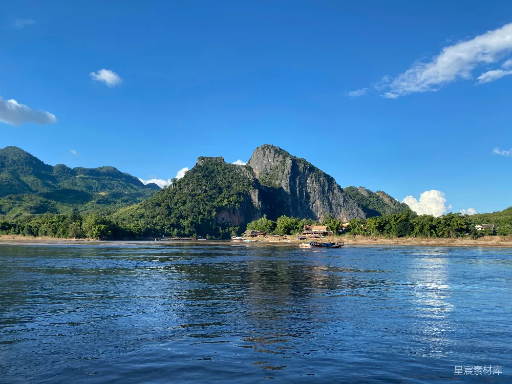 高清摄影  山峦俯瞰着一条宁静的河流，在一片明亮的蓝天之下。