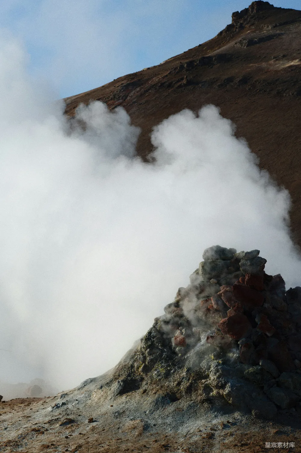 高清摄影  一群人站在一座山前，山里冒出蒸汽。