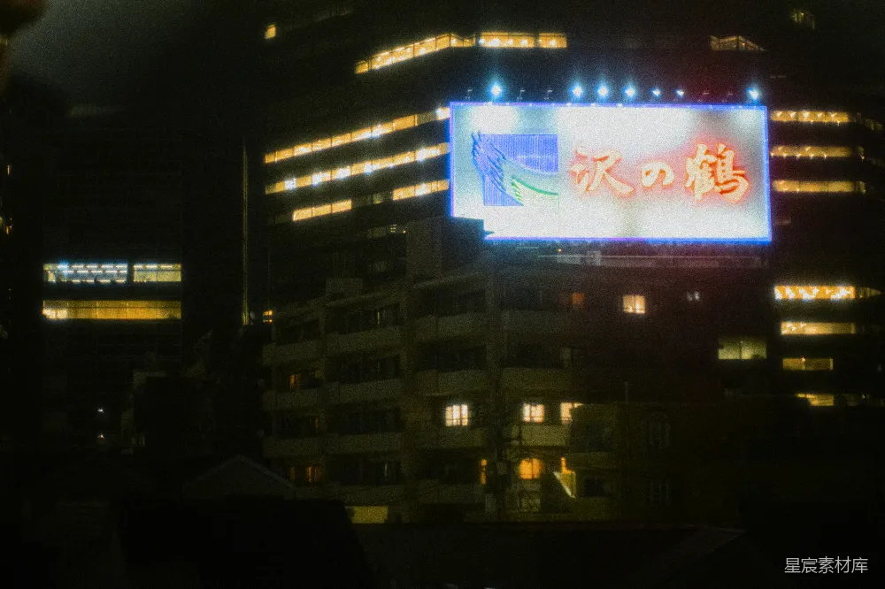 高清摄影  夜晚的城市，前景中有一个亮着的标志牌。