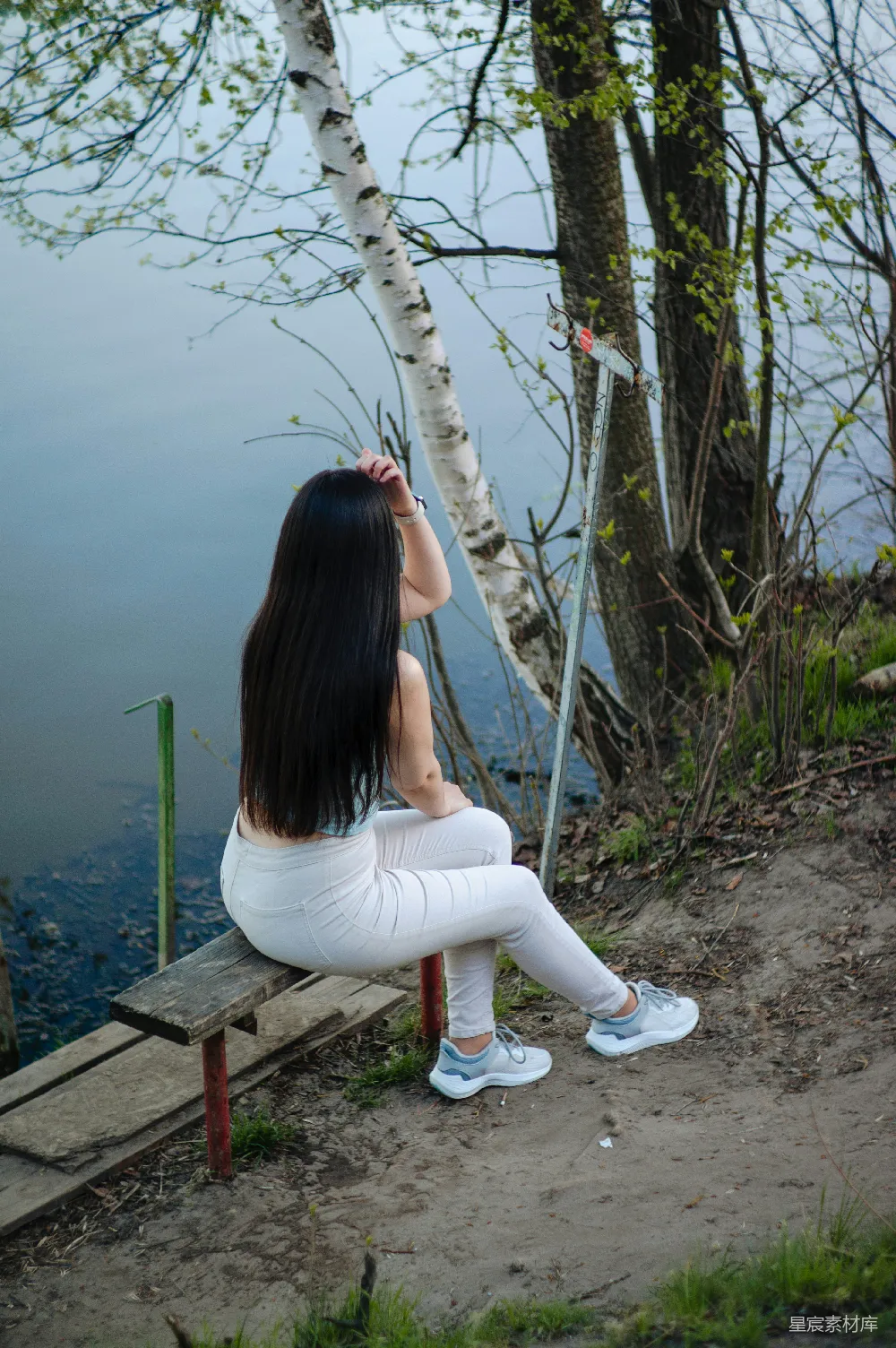 高清摄影  女人坐在长椅上，凝视着水面。