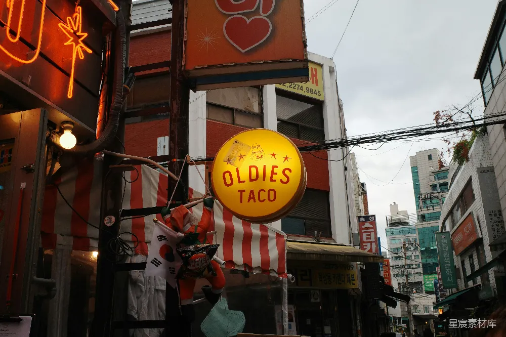 高清摄影  一个写着“老歌小吃卷饼”的招牌悬挂在城市街道上。
