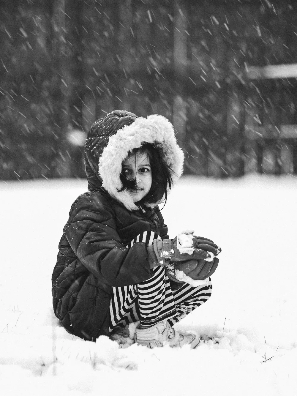高清摄影  一个小女孩戴着帽子坐在雪地里。