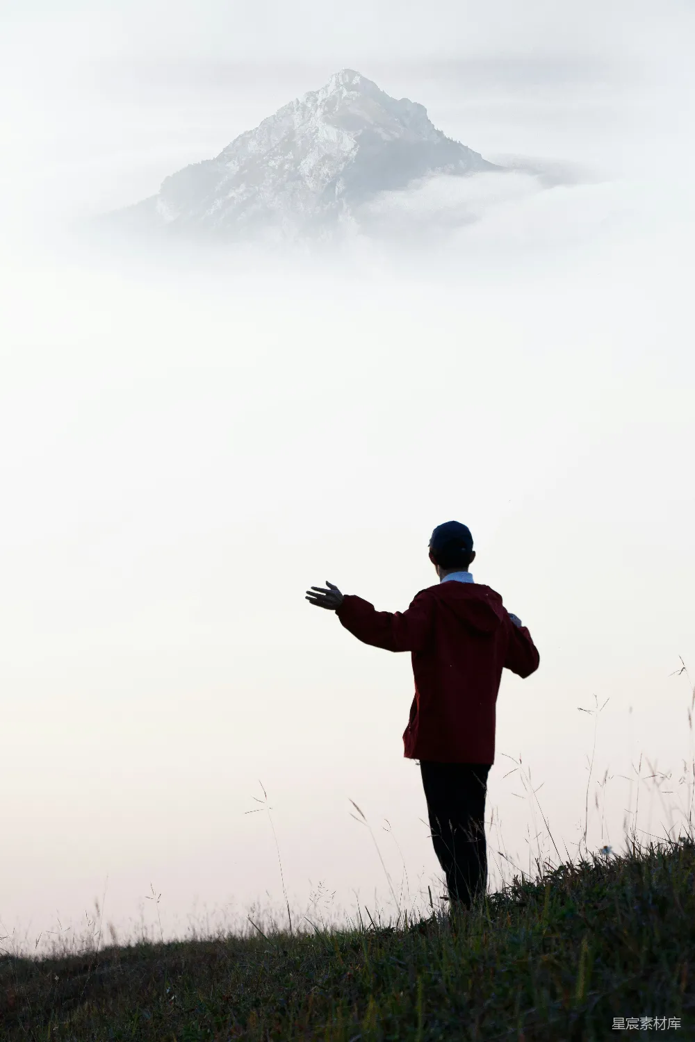 高清摄影  一个男人站在长满草地的小山上。