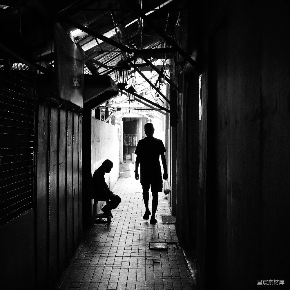 高清摄影  两个人沿着一条狭窄、黑暗的小巷行走。