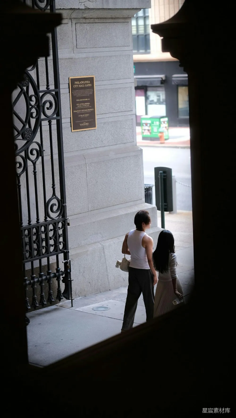 高清摄影  两个人走过一座装饰华丽的大门的建筑旁。
