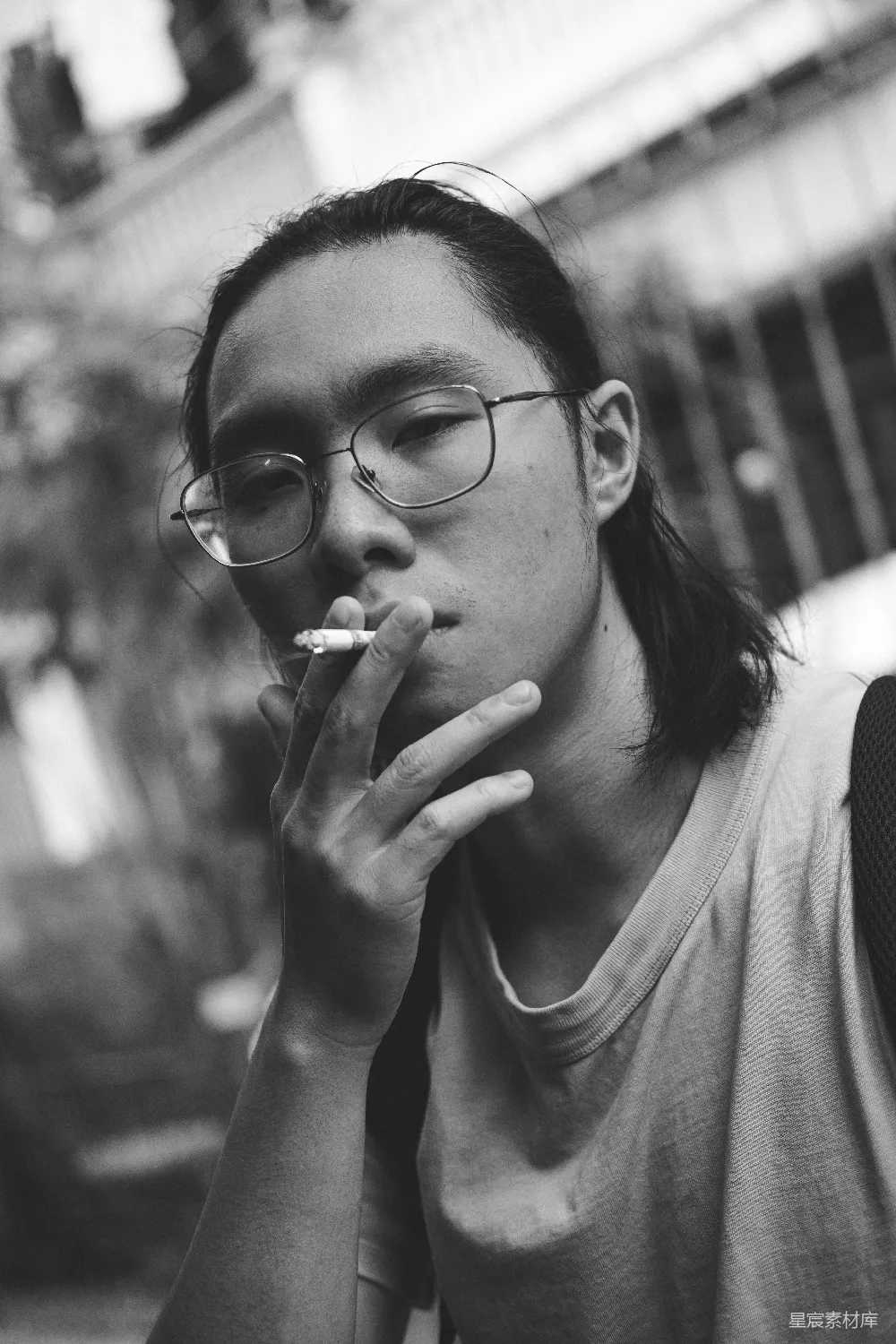 高清摄影  戴眼镜的男人在街上吸烟。