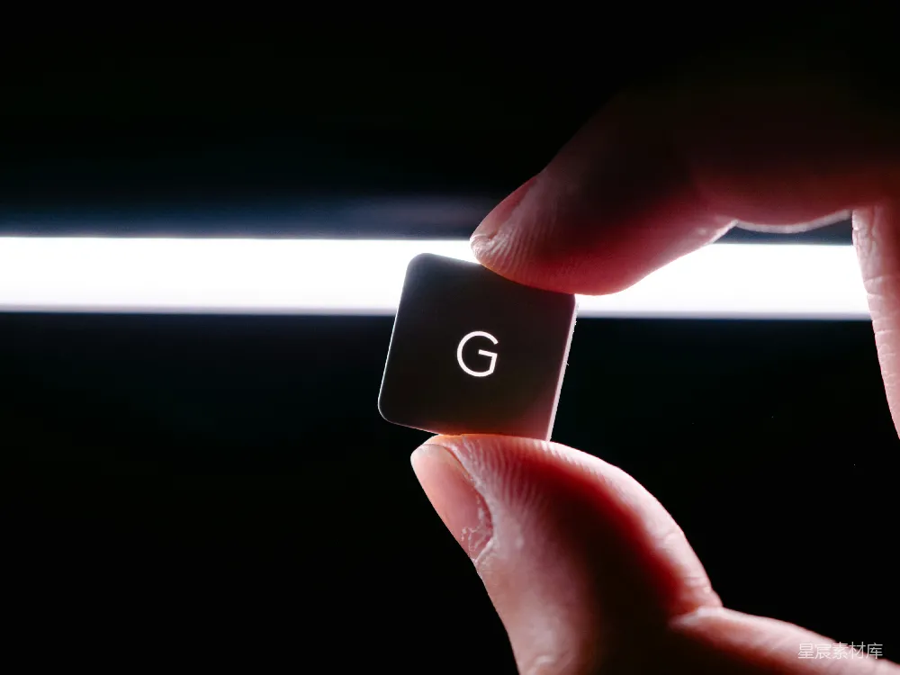 高清摄影  一只手拿着一个黑色的正方形物体，上面有字母"g"。