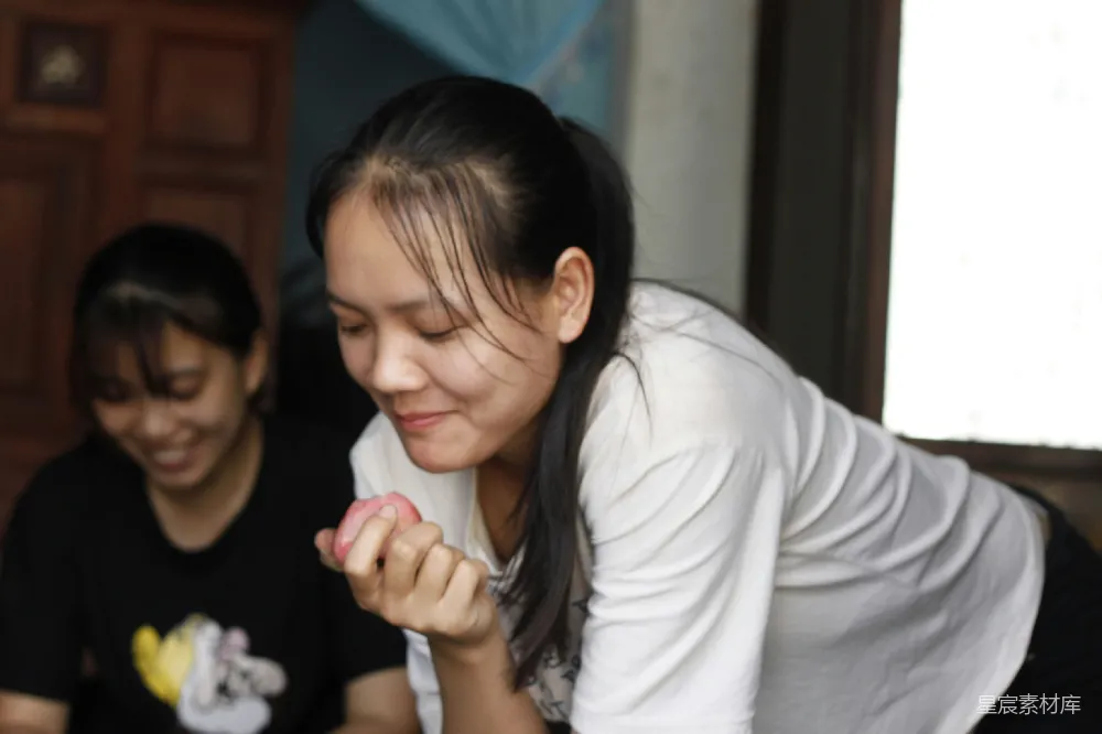 高清摄影  女人微笑着检查一个小小的粉红色物品。