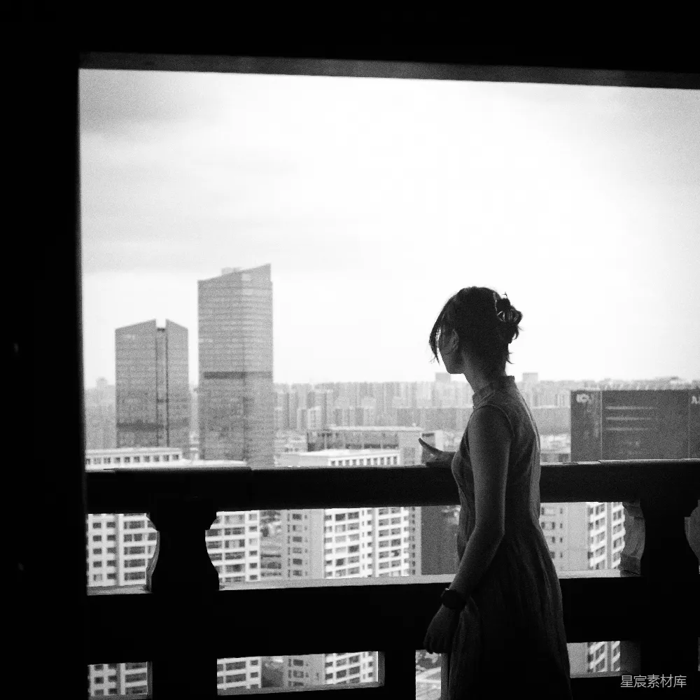 高清摄影  女人正望着窗外的城市天际线。