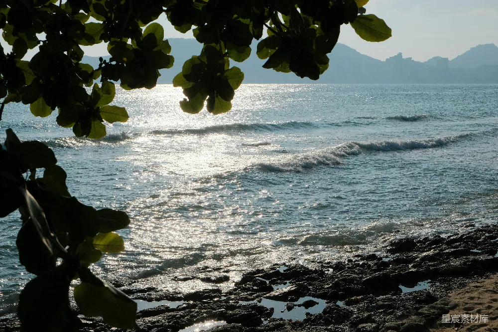 高清摄影  阳光在岸边岩石旁的海浪上闪烁。