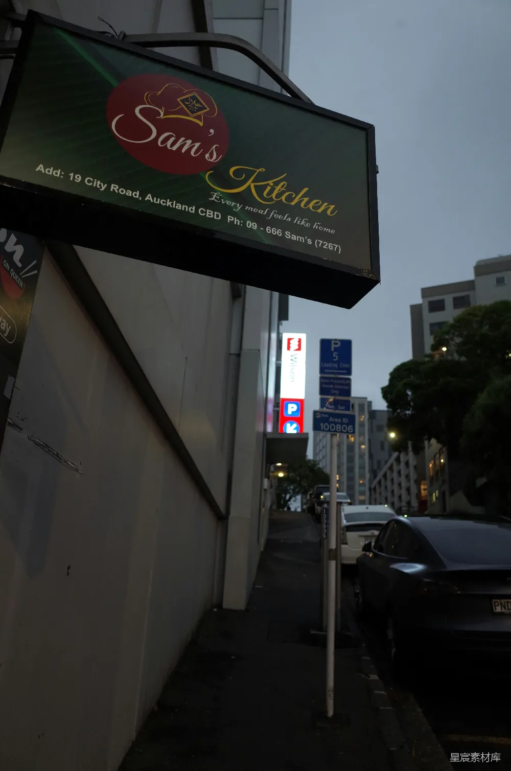 高清摄影  萨姆的厨房招牌在城市道路上亮着。